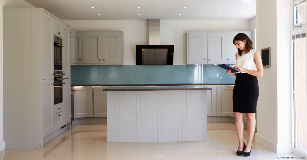 Female estate agent with a clipboard, standing in a kitchen.