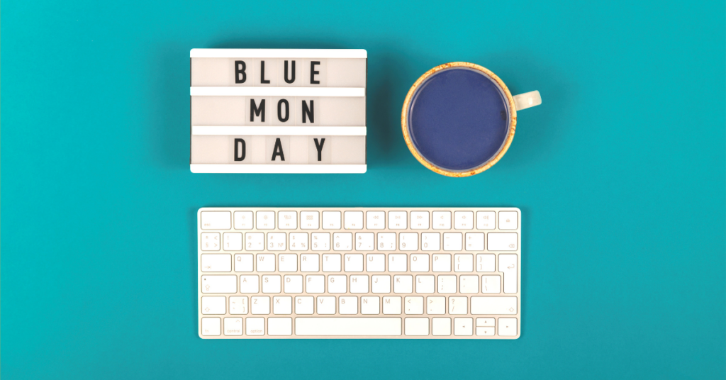 Blue desk, cup of coffee, keyboard, and "Blue Monday" text