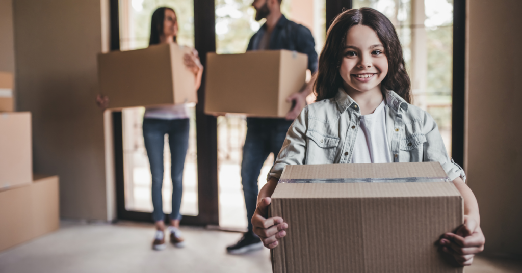 Little girl and her parents moving boxes into their new home.