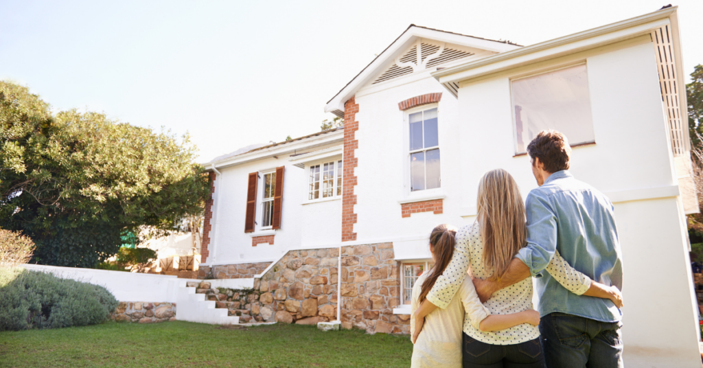 Family standing and hugging in front of new house