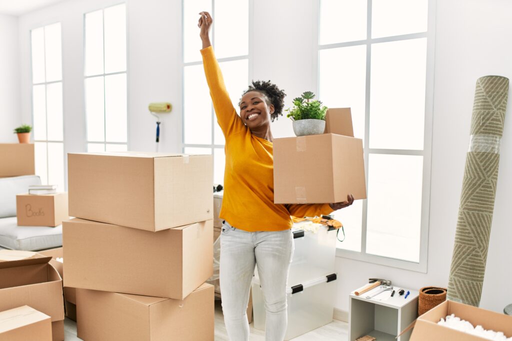 woman holding package standing with winner expression at new home