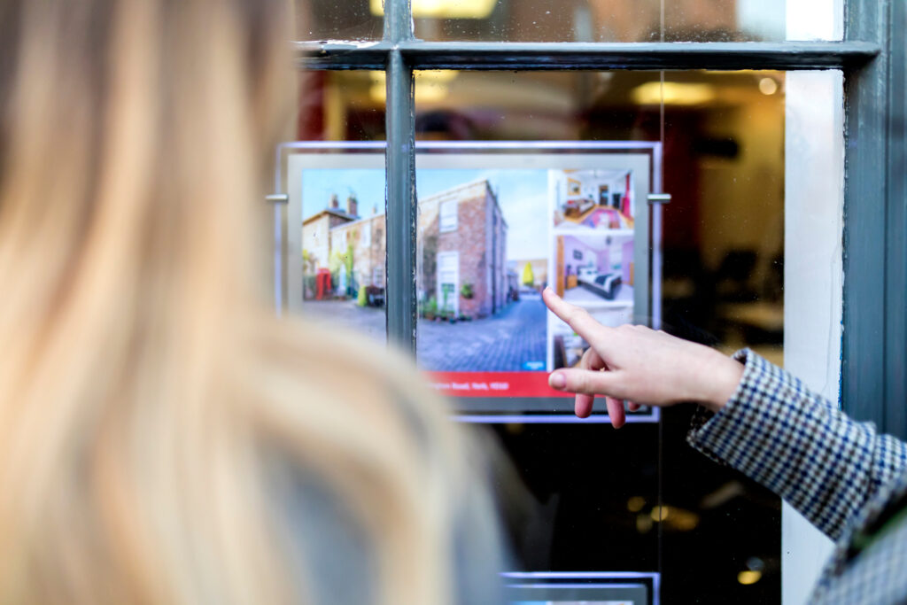 Couple looking at a property advert in the window of an estate agents or real estate shop window in England in the United Kingdom.