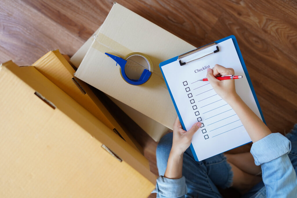 Top view of woman checking package with checklist at home