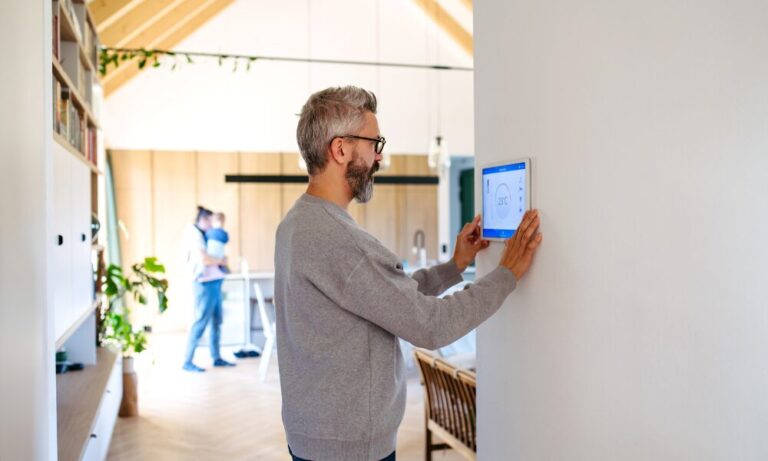 Man adjusting smart thermostat in a modern home, showing energy-efficient improvements for buy-to-let property in Chelmsford