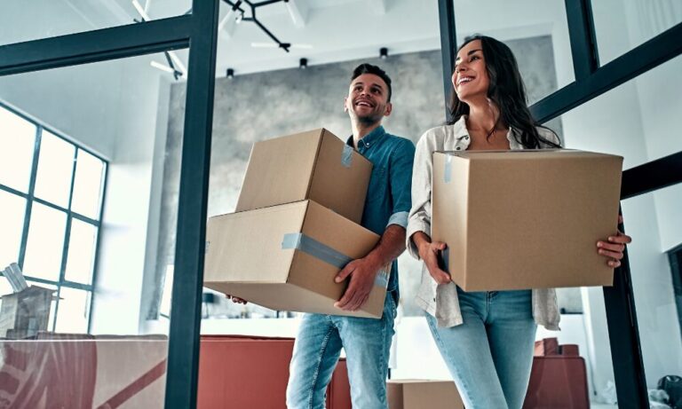 Couple carrying moving boxes into a modern home symbolising new housing developments in Wednesbury