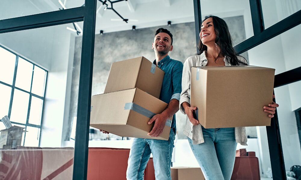 Couple carrying moving boxes into a modern home symbolising new housing developments in Wednesbury