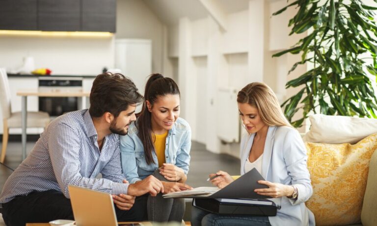 Couple reviewing property documents with an estate agent in a bright modern home, representing buying property in Lostock Gralam