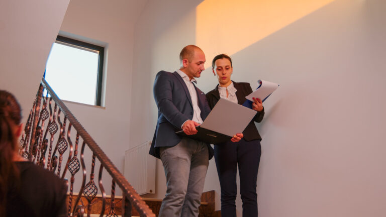 Estate agents reviewing property documents with a buyer in a stairway during a home viewing in Langton Green