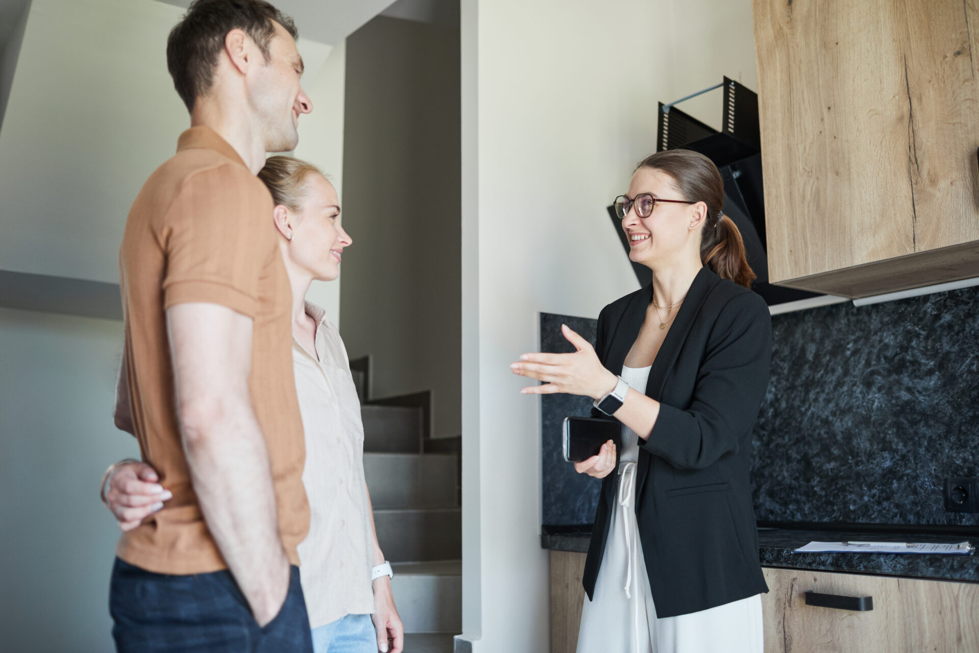 Estate agent showing a modern family home kitchen to a couple during a property viewing