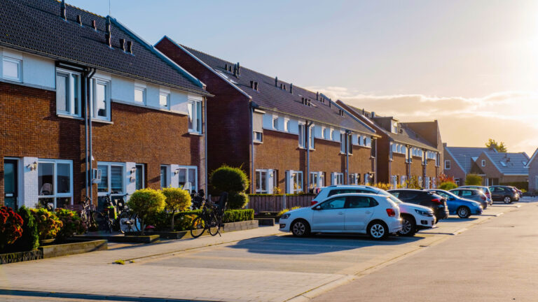 Row of modern family homes in Barnwood Gloucester with parked cars on a quiet residential street