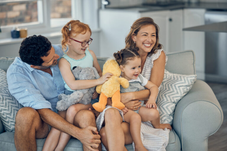 Happy family sitting on a sofa in a modern home, representing family life in Tamworth neighbourhoods