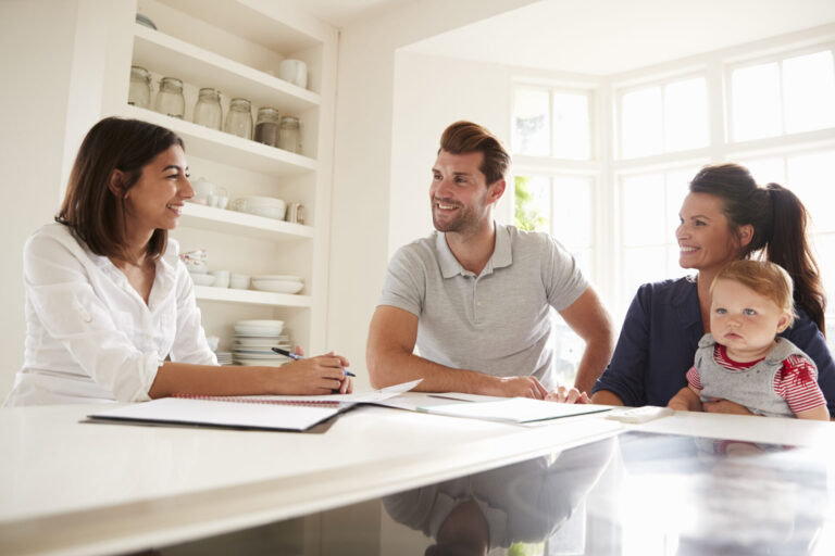 Estate agent discussing property options with a young family at a kitchen table