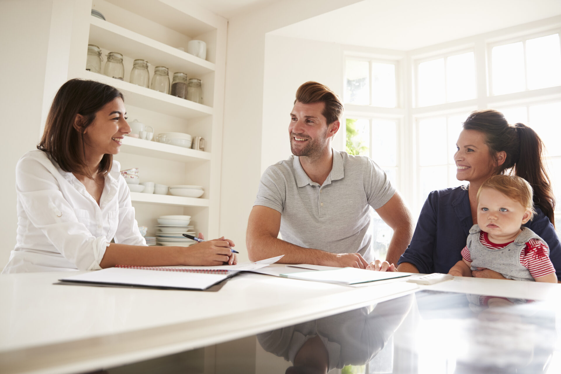 Estate agent discussing property options with a young family at a kitchen table