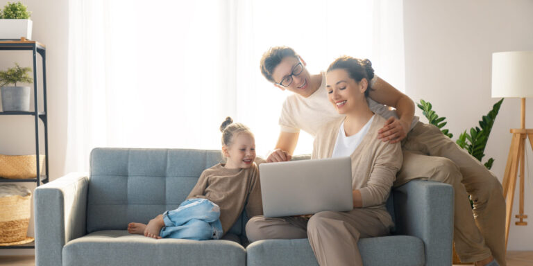 Family sitting on a sofa looking at a laptop while planning their move to a new home