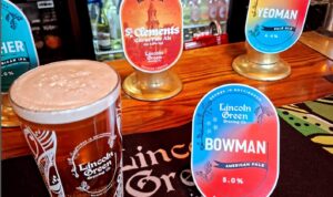 Pint of Lincoln Green ale on a pub bar with craft beer pumps and labels in a Carlton Nottingham pub setting
