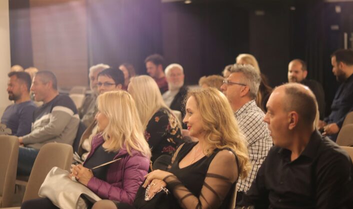 audience of adults attending a property auction event, seated and watching bidding proceedings