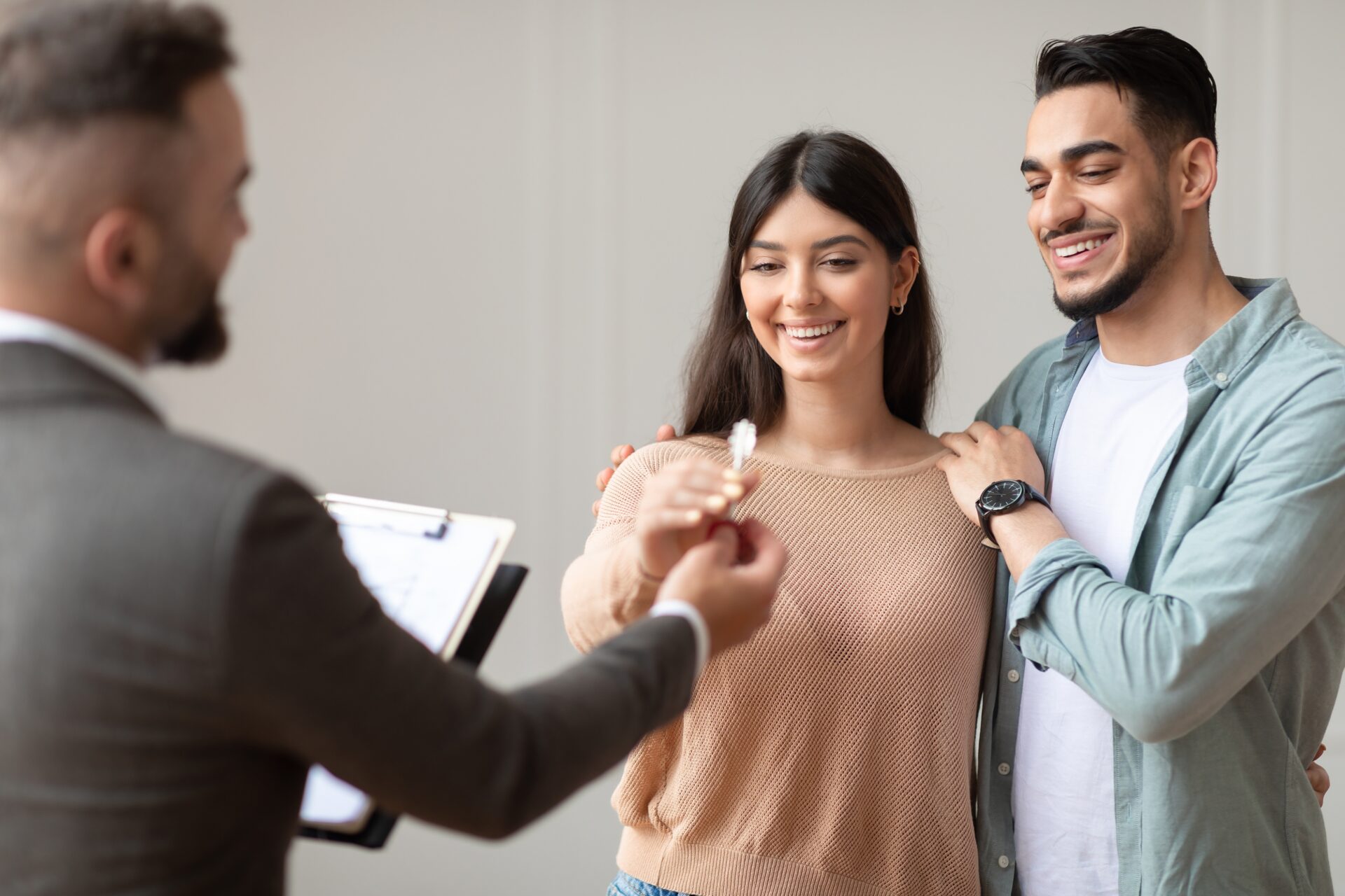 Young couple receiving house keys from an estate agent in Stafford buy-to-let property transaction