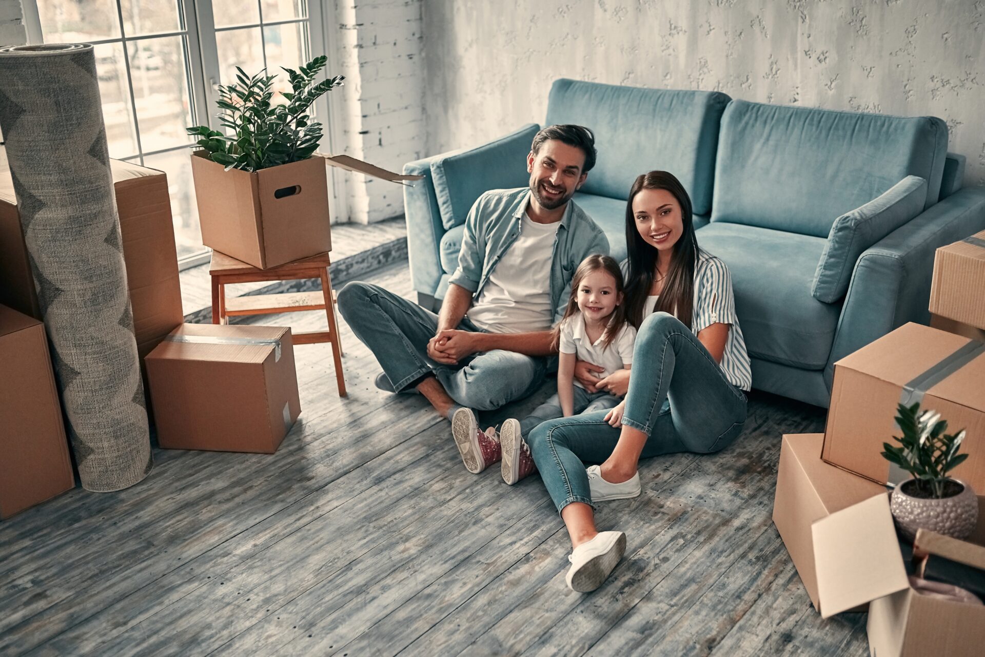 Young family sitting among moving boxes in a new rental property in Stone, Staffordshire