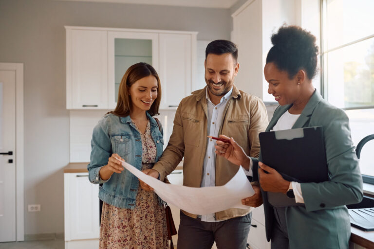 Estate agent discussing property details with a couple inside a modern new-build home, representing Doncaster rental investment advice.