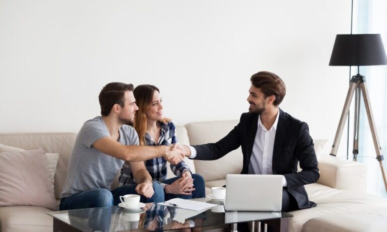 A Belvoir Tadley estate agent shakes hands with a couple after discussing property details in their home, representing a successful property purchase or tenancy agreement in Baughurst RG26.