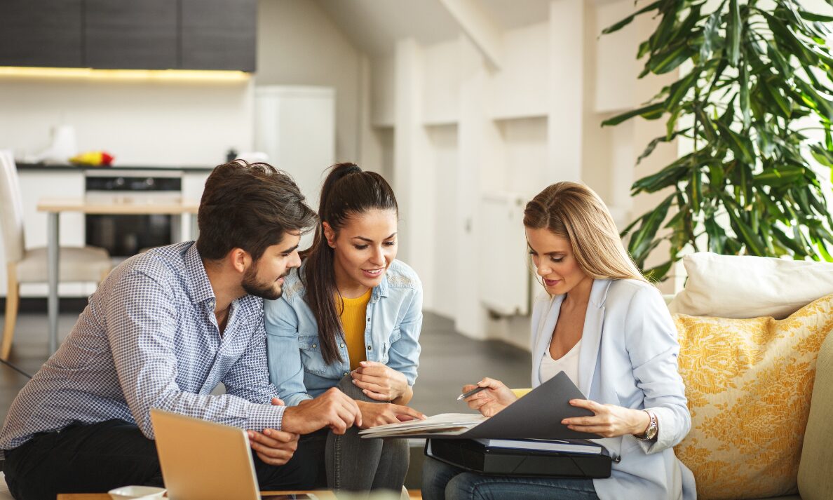 Estate agent discussing property documents with a couple in a modern home, representing house prices and buyer demand in Pontypridd.