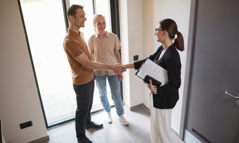 Estate agent welcoming a couple with a handshake at the entrance of a modern home, representing the buying, renting and property opportunities available across RH15, including Burgess Hill and Wivelsfield.