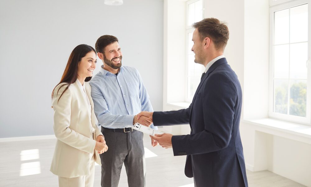 Estate agent shaking hands with a couple after a successful property viewing, representing the buying and property opportunities available in the St Neots PE19 area.