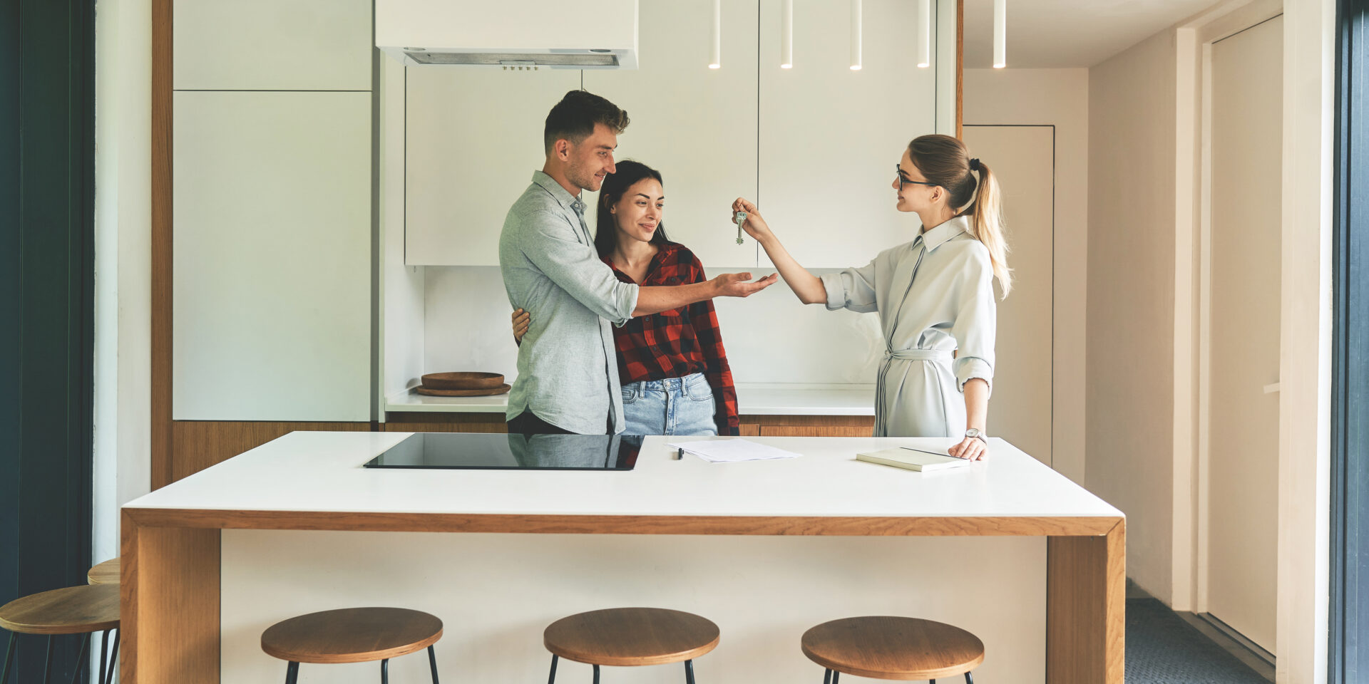 Estate agent handing keys to a couple in a modern kitchen, representing house valuations and buyer demand in Tamworth.