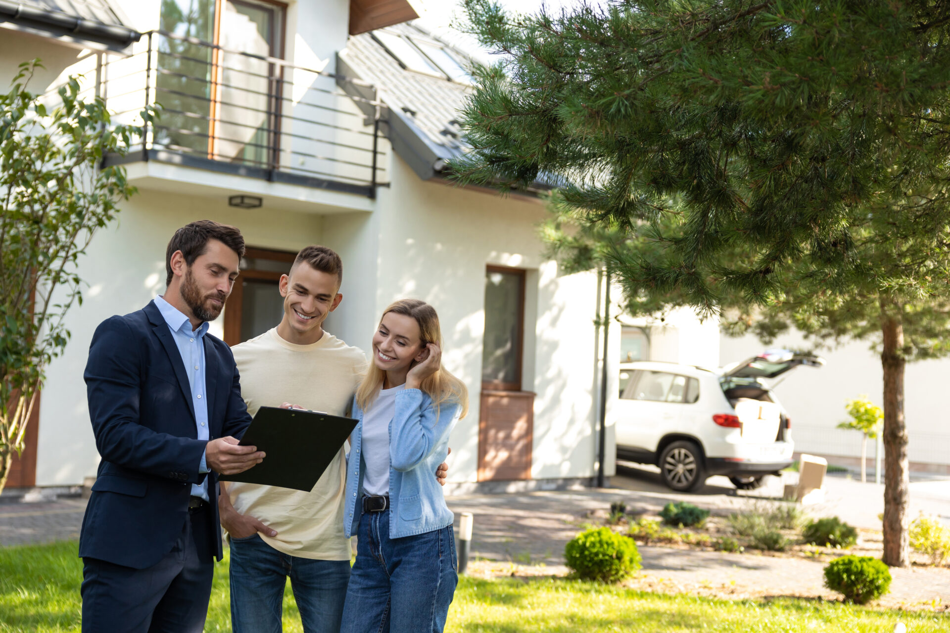 Estate agent showing a couple property details outside a modern home, representing Tamworth landlord compliance and rental demand in B77 and B79.