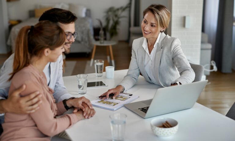 An estate agent discusses property options with a couple during a home-buying consultation, reflecting the process of comparing neighbourhoods and property prices in St Helens for buyers in 2026.