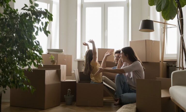 A young family sits among moving boxes in their new home, celebrating moving day. The image reflects the journey of first-time buyers purchasing a property in Shrewsbury's SY1 and SY2 neighbourhoods.