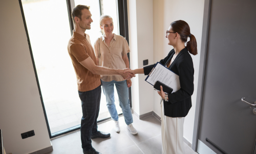 Estate agent welcoming prospective buyers during a viewing of a modern home, illustrating the buying process for new-build properties in Brighton and supporting an article comparing new-build and period homes in the 2026 property market.