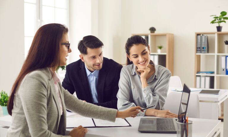 Estate agent discussing property details with a couple using a laptop during a home-selling consultation, illustrating expert advice for homeowners preparing to sell in Walsall's 2026 property market.
