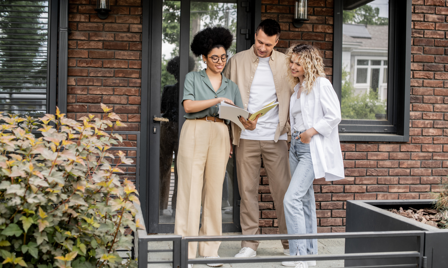 Letting agent reviewing property documents with two renters outside a rental home