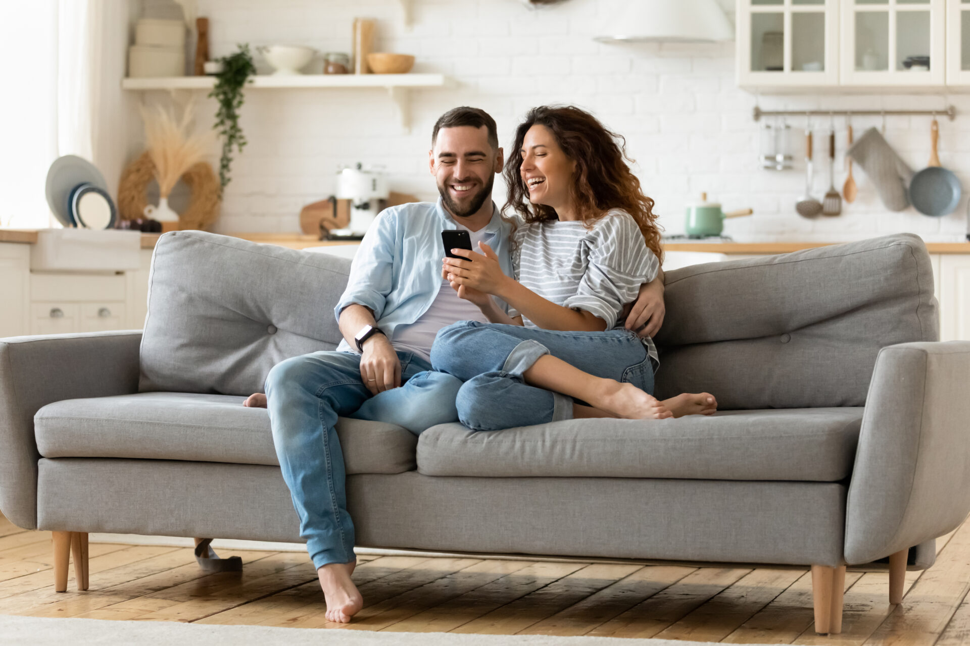 Couple relaxing together on a sofa while looking at a smartphone, representing the lifestyle and rental appeal of Bessacarr DN4.