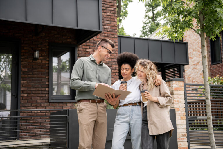 Property agent discussing rental property with prospective tenants outside a modern home, representing Wigan rental demand in 2026.
