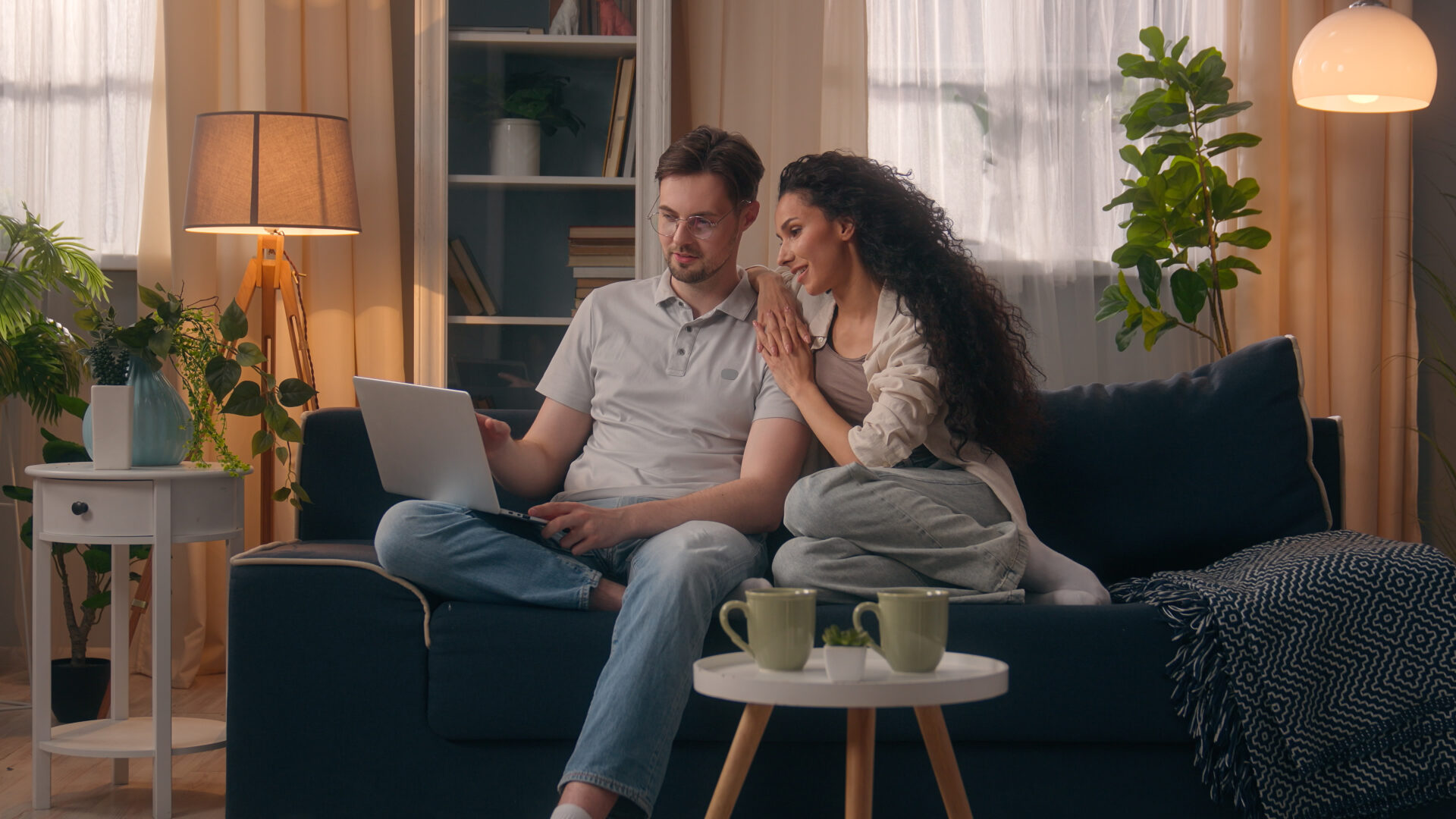 Couple using a laptop together while relaxing in their rented home