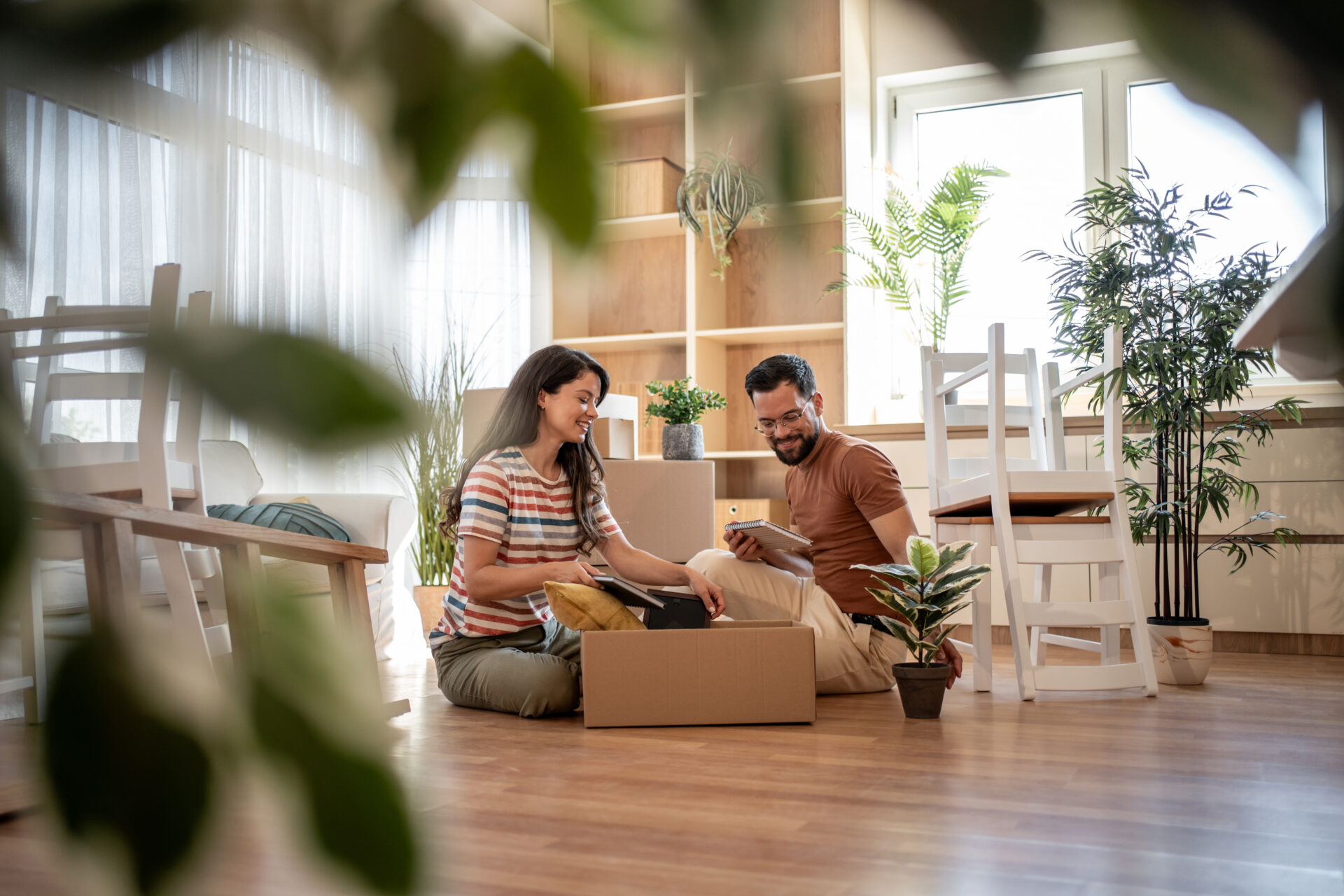 Couple preparing to move home while sitting with moving boxes in a bright living room
