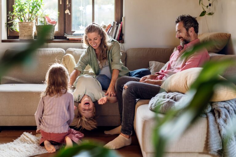 Parents playing with their two young children in a sunny living room, showing family life in Guiseley LS20
